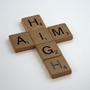 Wooden scrabble pieces on a white background spelling out aim high