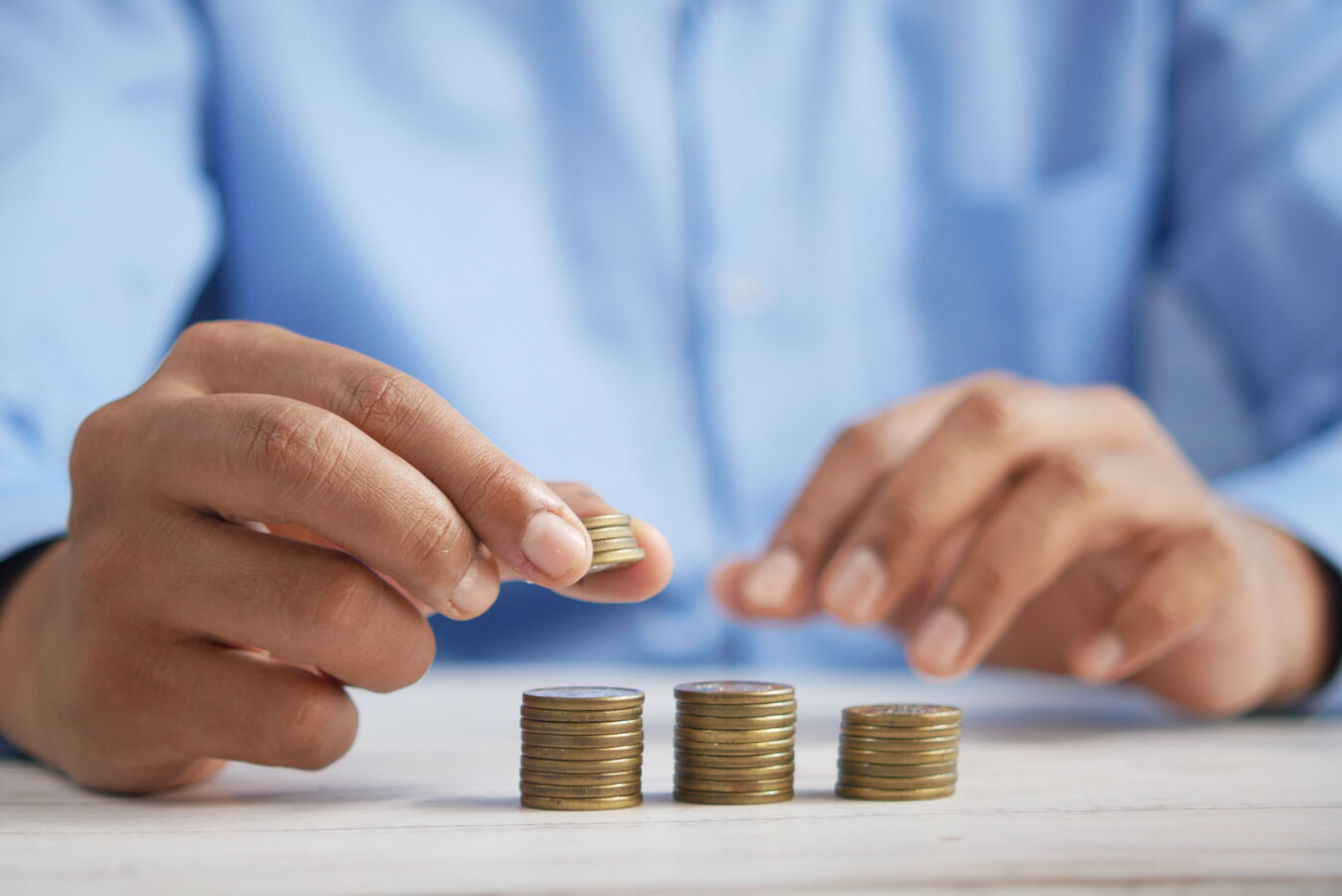 A man's hands zoomed in on creating three piles of brass coloured coins