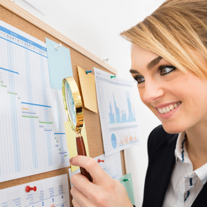 Businesswoman examining a Gantt chart With a magnifying glass