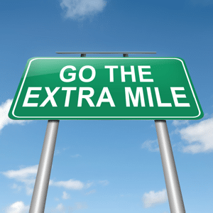 A green road sign reading go the extra mile