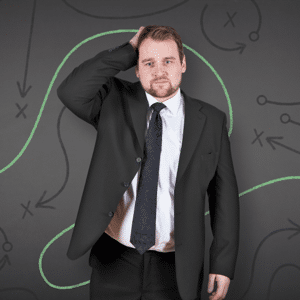 Businessman looking puzzled in front of a blackboard