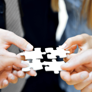 Four business people's hands holding puzzle pieces