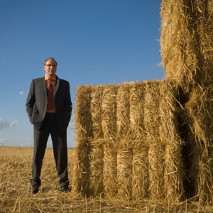 Businessman in a cornfield standing next to a haystack