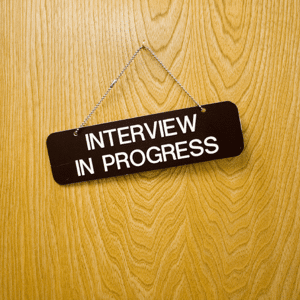 Black sign on a wooden office door reading interview in progress