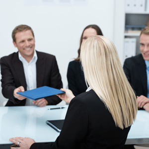 Blond female job applicant handing over her CV to a smiling businessman