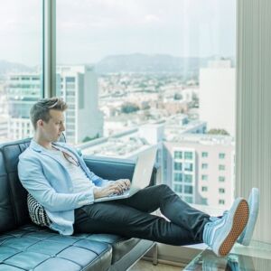 Ein junger Mann arbeitet an einem Laptop in einem Penthouse mit Blick auf die Stadt