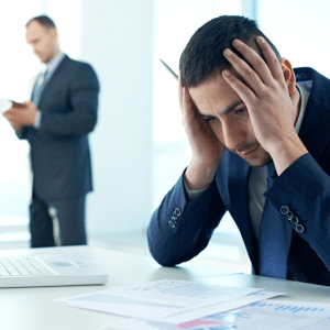 Worried businessman sitting at an office desk with documents overloaded with work