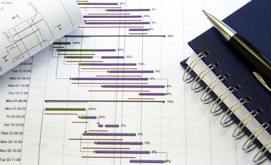 A Gantt chart, pen and notebook