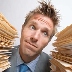 Businessman looks perplexed choosing between two huge stacks of files