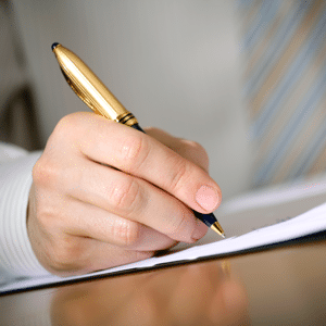 Close-up of a businessman's hand with a gilded pen writing a document