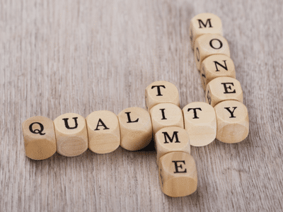 Closeup of Quality, Time and Money cubes arranged on wooden table