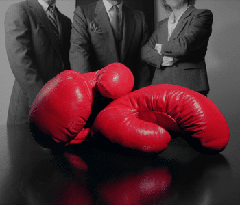 Close-up of red boxing gloves and business people