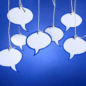 Seven white speech bubbles hanging down on strings against a blue background