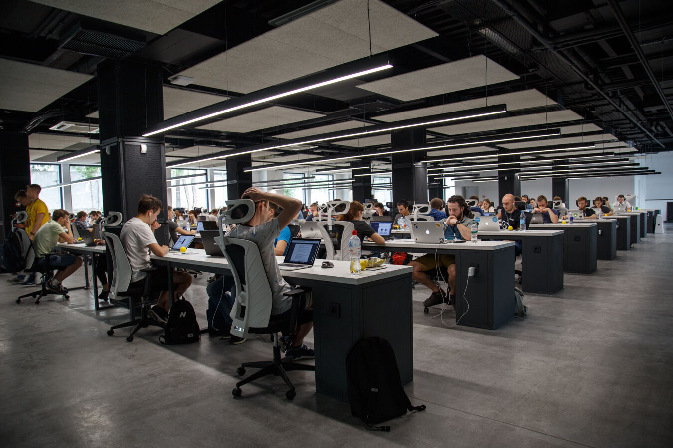 A modern office floor full of people working behind laptops