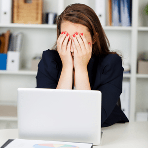 Businesswoman sitting at a desk with her hands covering her eyes