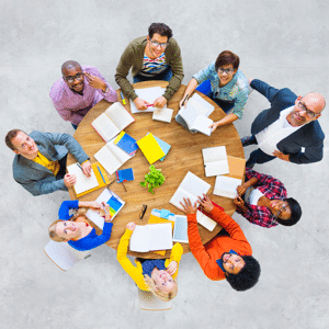 Large business team gathered around a wooden table looking up