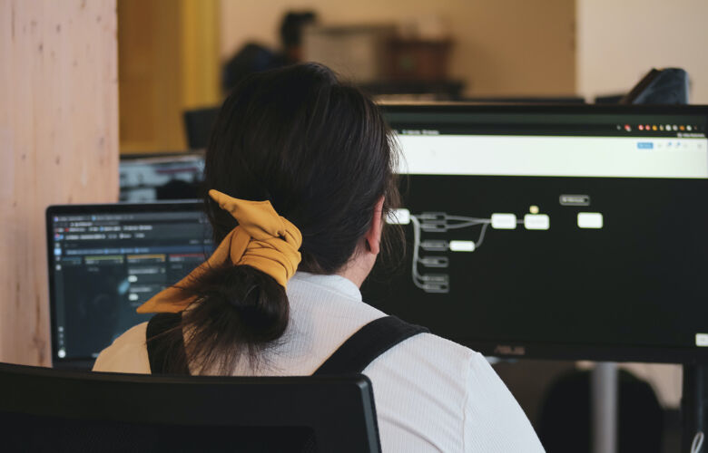 A software developer at a computer photographed from behind designing a new program