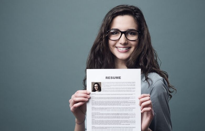 Young smiling and cheerful woman holding up her resume