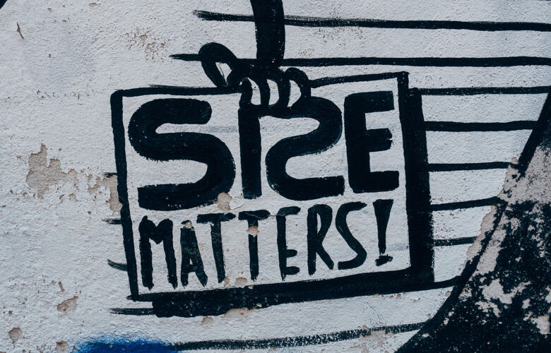 The words size matters in black paint on a white building wall