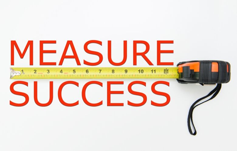 The words measure success split by a yellow steel tape measure